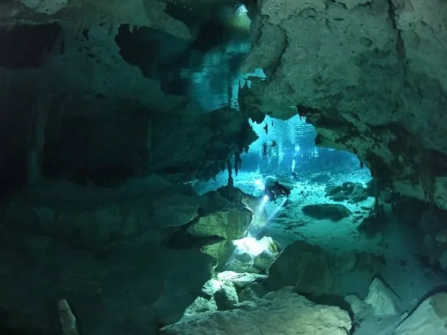 Sporttaucher mit Taschenlampen erkunden die spektakulären Unterwasserhöhlen im Cenote Dos Ojos.